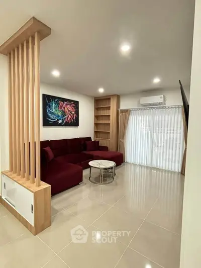Modern living room with elegant red sofa, stylish decor, and natural light from large windows.
