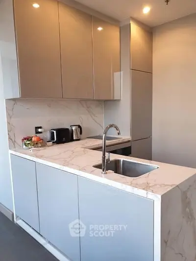Modern kitchen with sleek cabinets and marble countertops, featuring a stylish sink and appliances.