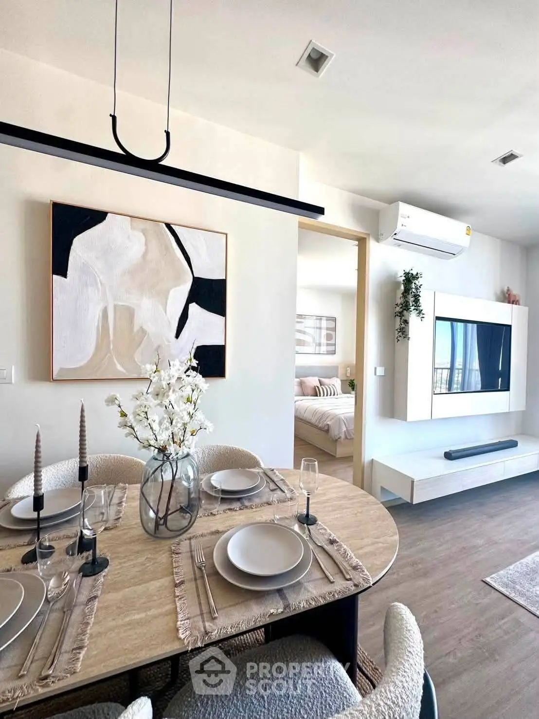 Modern dining area with elegant table setting and view into cozy bedroom, featuring stylish decor and natural light.