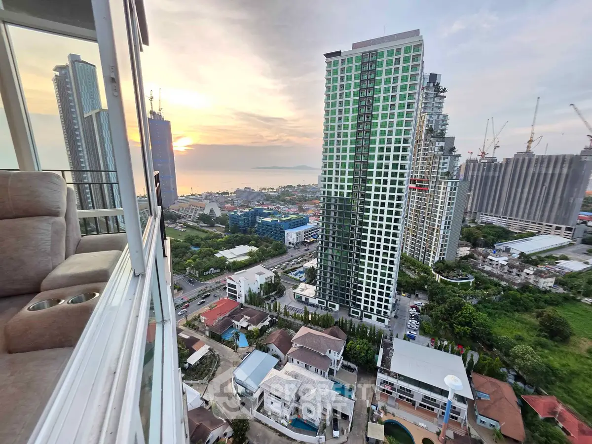 Stunning high-rise view of cityscape and ocean at sunset, showcasing modern urban living.