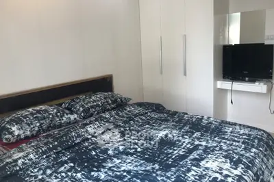 Modern bedroom with stylish bedding and wall-mounted TV in a sleek apartment.