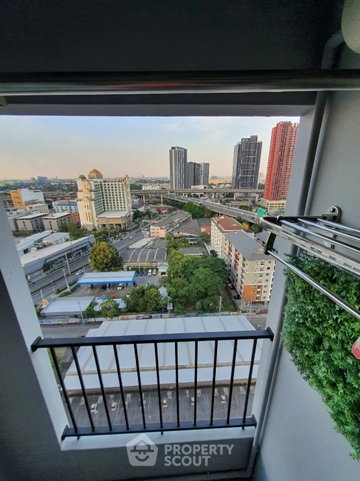 Stunning cityscape view from a high-rise balcony with lush greenery and urban skyline.