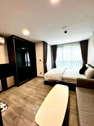 Modern bedroom with large window and stylish furnishings in a contemporary apartment.