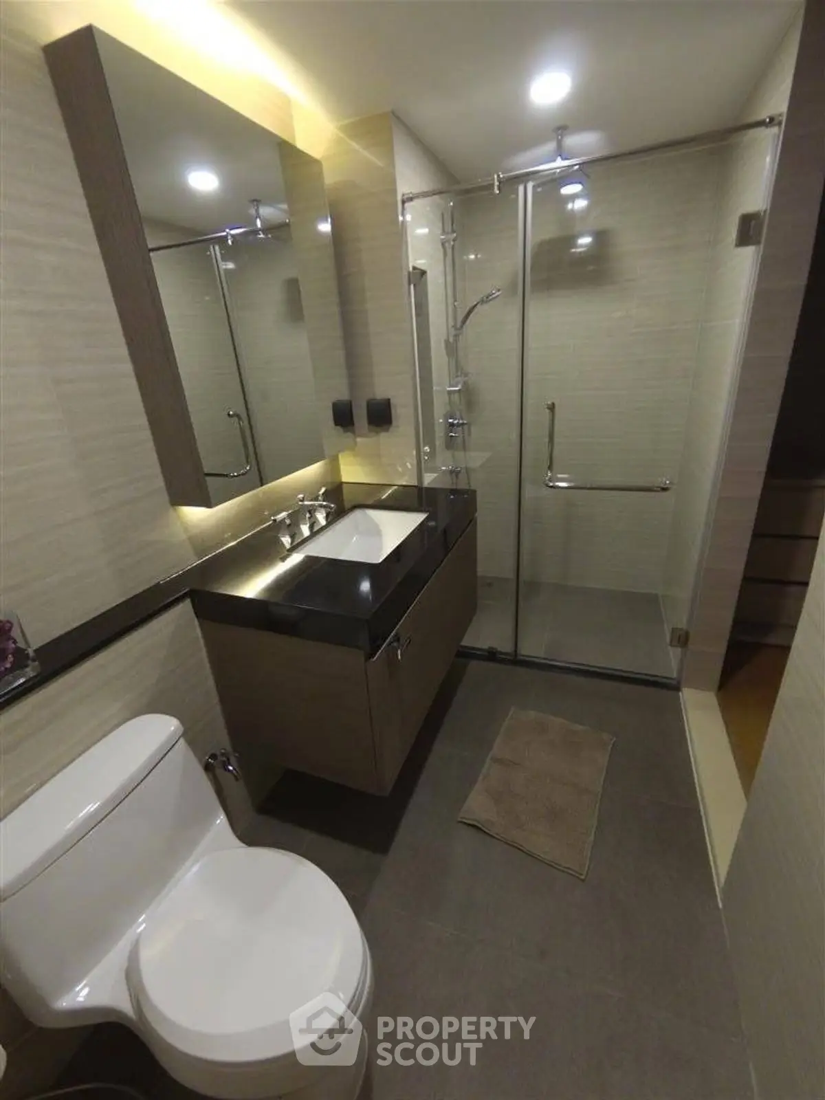 Modern bathroom with glass shower and sleek vanity in contemporary apartment.