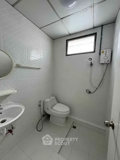 Compact bathroom with modern fixtures and shower in a bright, tiled space.