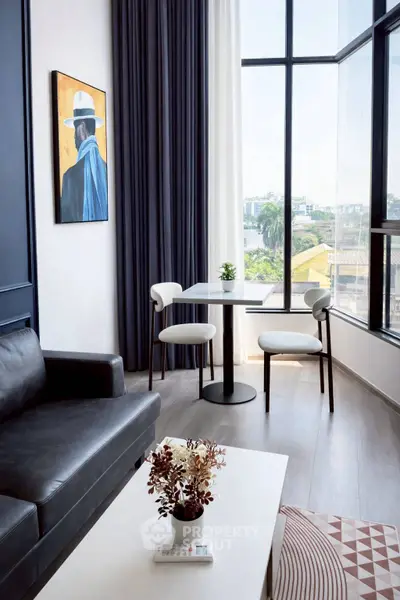 Modern living room with large windows and stylish decor in a high-rise apartment.