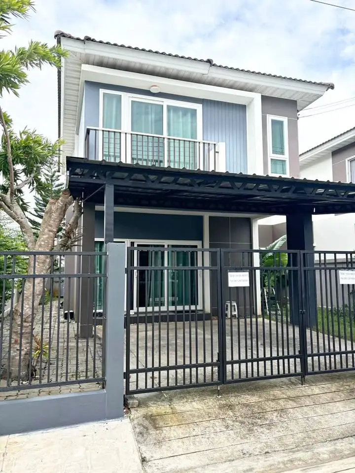 Modern two-story house with balcony and gated driveway in suburban neighborhood.