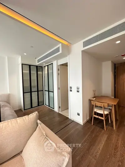 Modern living room with elegant wood flooring and cozy seating area, featuring a stylish glass partition.