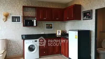 Charming kitchen with elegant wooden cabinets, washing machine, and compact fridge, perfect for modern living.