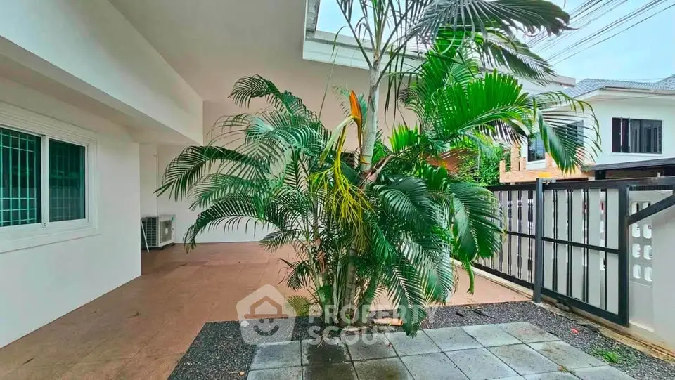 Spacious outdoor area with lush greenery and tiled flooring in a modern residential property.