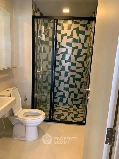Modern bathroom with geometric tile shower and sleek fixtures.