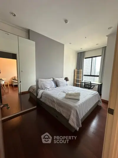 Modern bedroom with city view and elegant furnishings in a high-rise apartment.