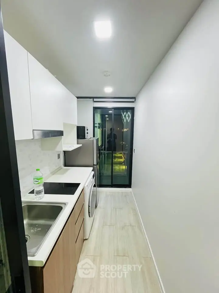 Modern kitchen with sleek design, featuring built-in appliances and a view of the balcony.