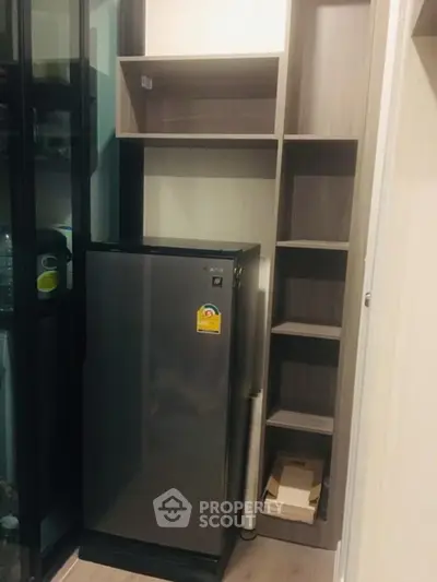 Compact kitchen storage with modern fridge and shelving in stylish apartment.