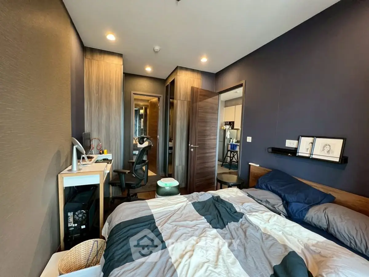 Modern bedroom with stylish decor and workspace, featuring cozy bedding and sleek furniture.
