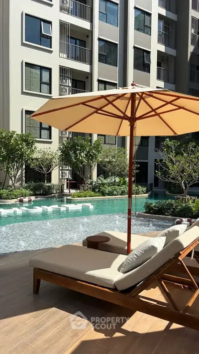 Luxurious apartment complex with inviting poolside area and sun loungers under umbrellas.
