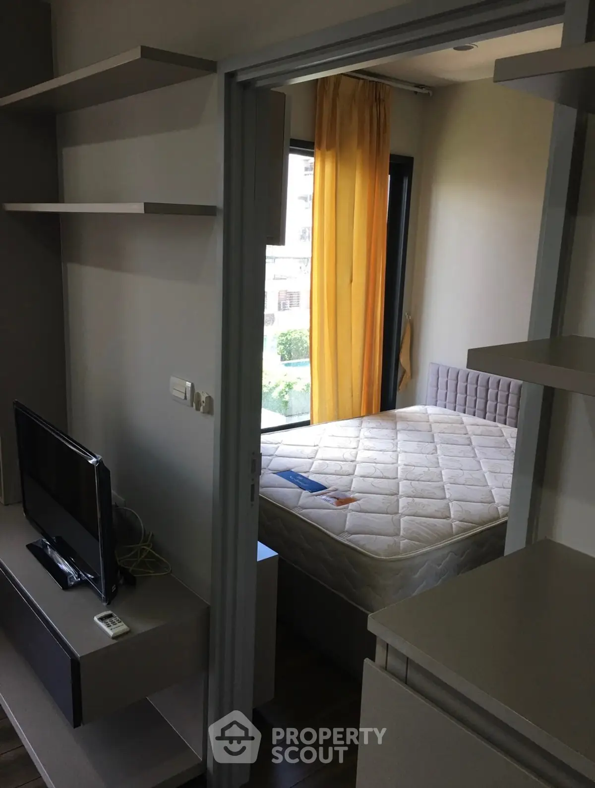 Cozy bedroom with modern decor and natural light, featuring a comfortable bed and stylish shelving.