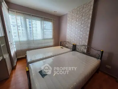 Spacious bedroom with twin beds and large window offering natural light