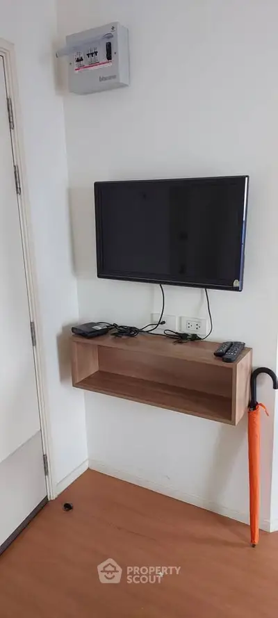 Modern living room corner with wall-mounted TV and sleek wooden shelf
