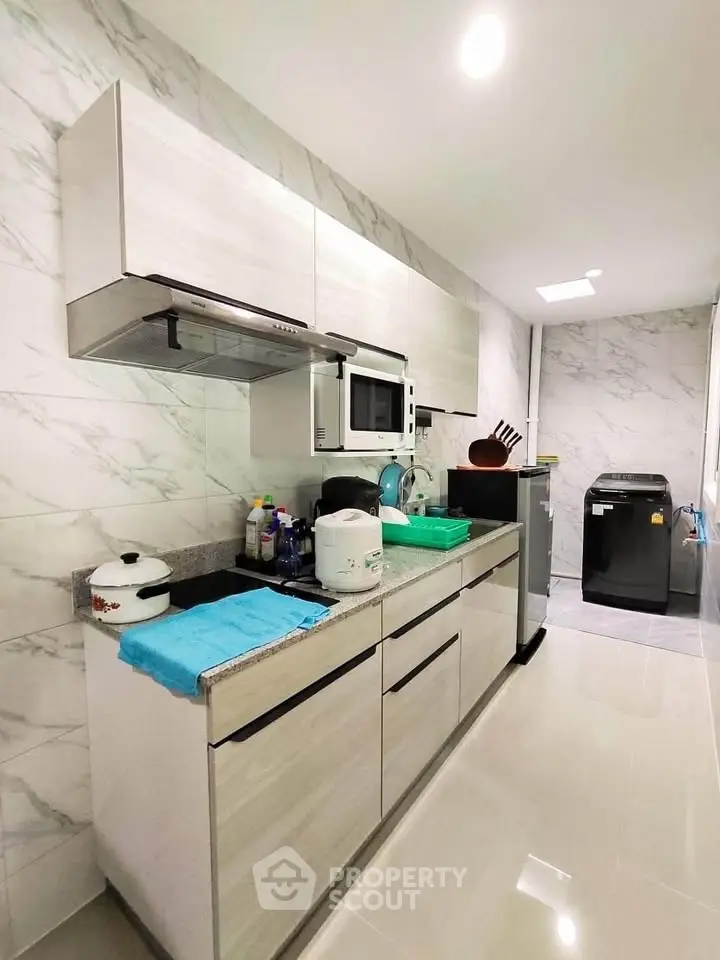 Modern kitchen with sleek cabinets and marble backsplash, featuring appliances and ample counter space.