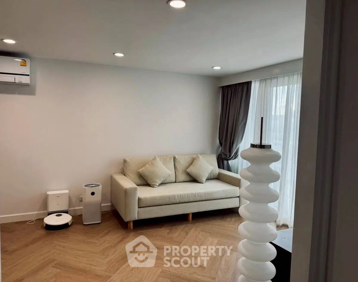Modern living room with stylish sofa and wooden flooring, featuring a sleek air conditioner and natural light.