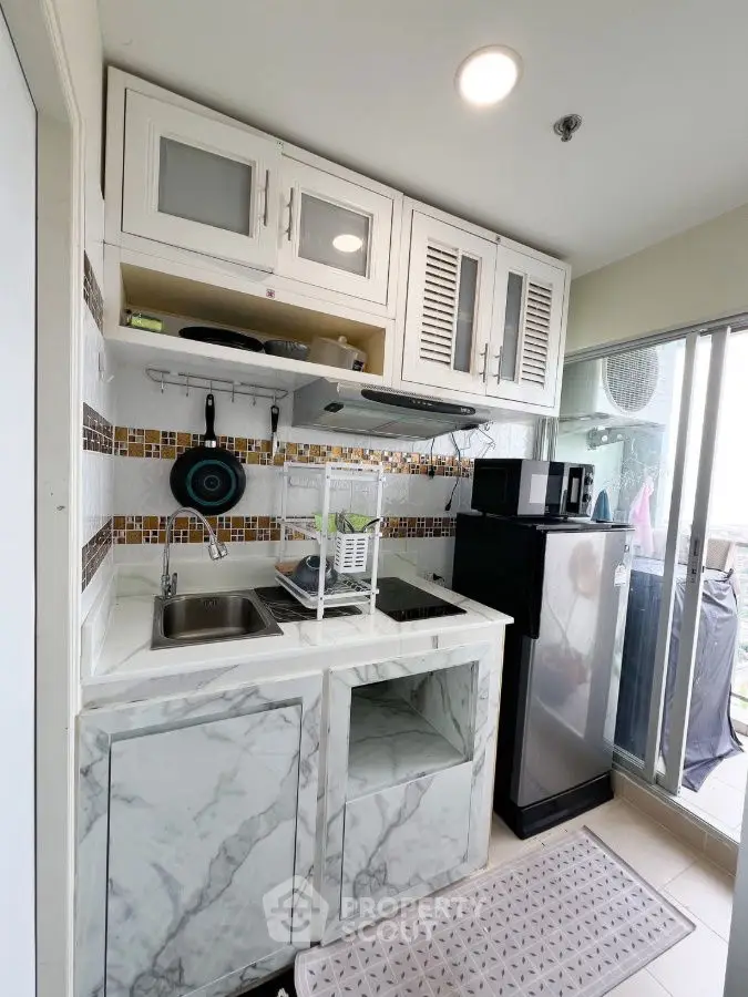 Compact kitchen with marble countertops and modern appliances in a cozy apartment.