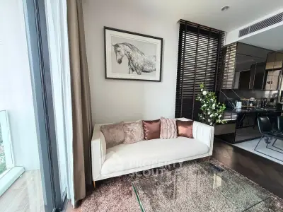 Modern living room with elegant decor and open kitchen layout, featuring a cozy sofa and stylish glass table.