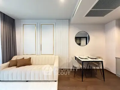 Modern living room with elegant sofa and dining area, featuring stylish decor and warm lighting.