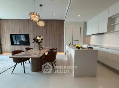 Luxurious modern kitchen with open layout and elegant dining area, featuring stylish lighting and sleek cabinetry.