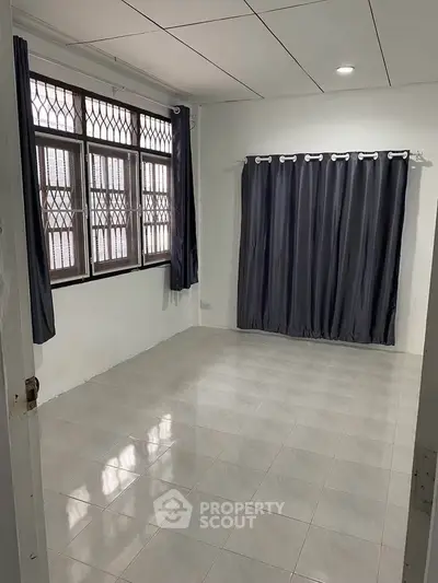 Spacious empty room with tiled floor and large windows, perfect for customization.