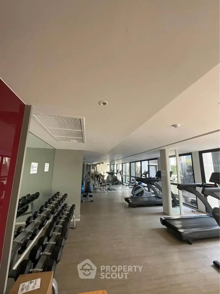Spacious modern gym with state-of-the-art equipment and large windows for natural light.
