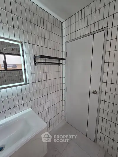 Modern bathroom with sleek white tiles and illuminated mirror