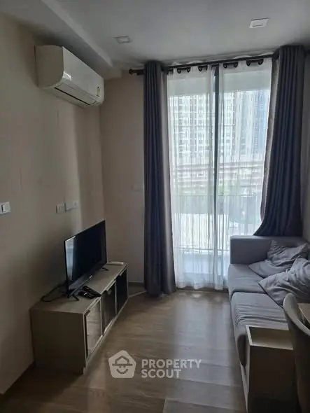 Cozy living room with modern decor and large window view in urban apartment.