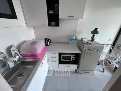 Compact kitchen with modern appliances and sleek white cabinetry