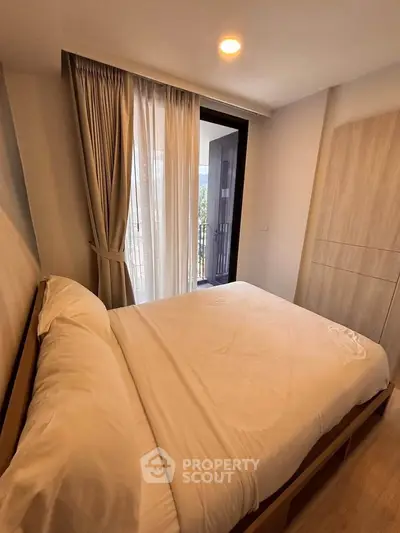 Cozy bedroom with balcony access and natural light in modern apartment.