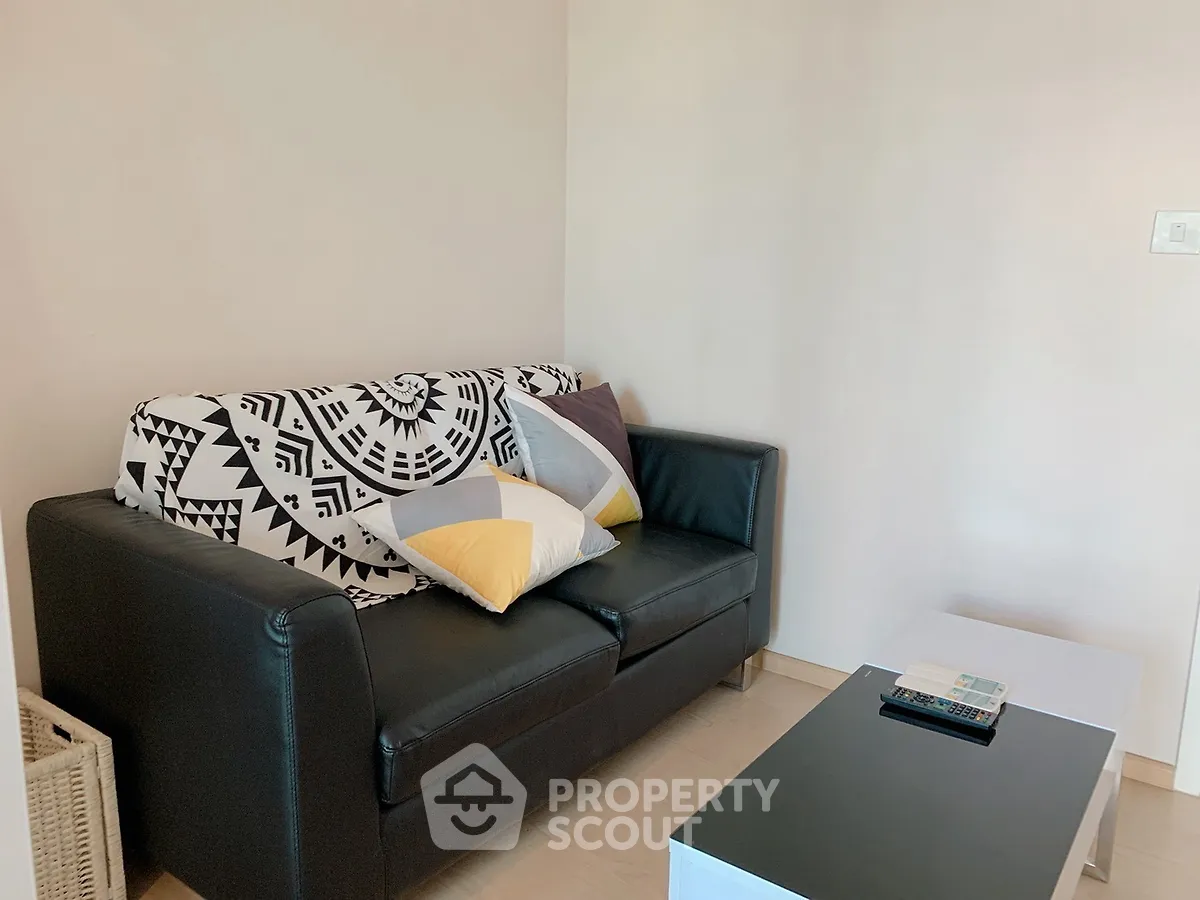 Cozy living room with stylish black sofa and modern coffee table, perfect for relaxation.
