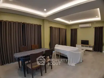 Spacious living room with modern ceiling lights and air conditioning, featuring a dining area and covered furniture.