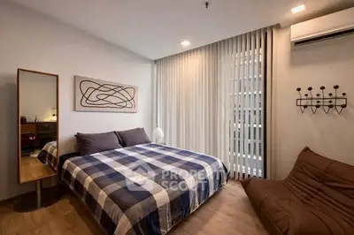 Modern bedroom with stylish decor and natural light, featuring a cozy bed and contemporary furnishings.