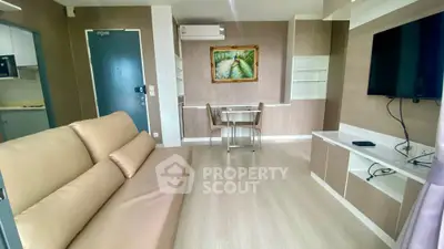 Modern living room with beige sofa, wall-mounted TV, and dining area in open layout.