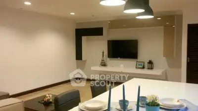 Modern living room with sleek TV setup and elegant dining area, perfect for entertaining.