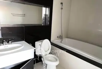 Modern bathroom with sleek black and white design featuring bathtub and sink.