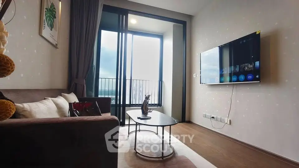Modern living room with balcony view, stylish decor, and wall-mounted TV in a cozy apartment.