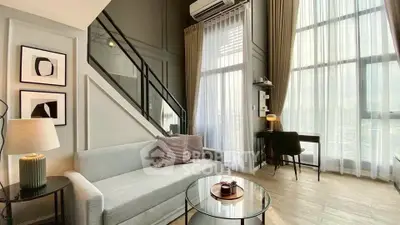 Modern living room with high ceilings and large windows, featuring stylish decor and a cozy ambiance.