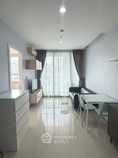 Modern living room with sleek furniture and large window offering city views.