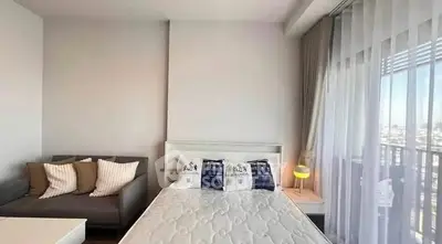 Modern bedroom with cozy sofa and large window offering city views