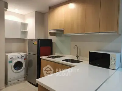 Modern kitchen with washing machine, fridge, and microwave in compact layout.