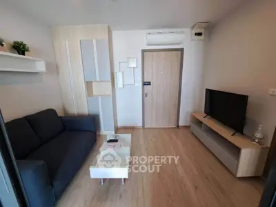 Modern living room with sleek furniture and wooden flooring, featuring a cozy sofa and a flat-screen TV.