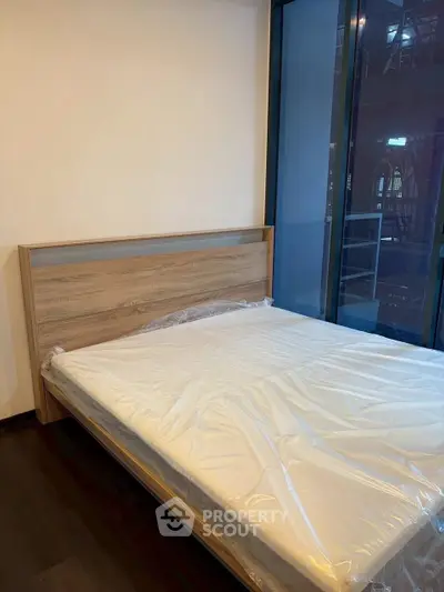 Modern bedroom with large window and wooden bed frame, perfect for urban living.