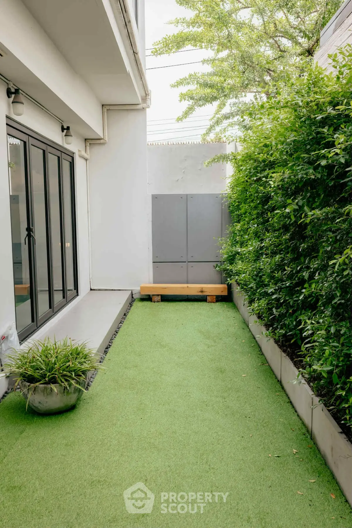 Charming garden area with lush greenery and modern patio design, perfect for relaxation.