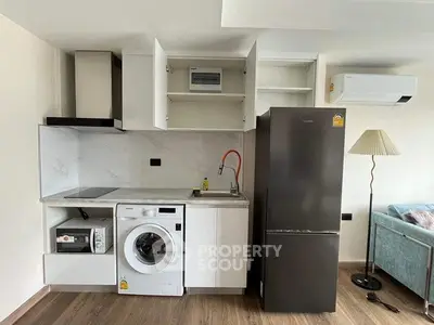 Modern kitchen with appliances including washing machine, fridge, and microwave in a stylish apartment.